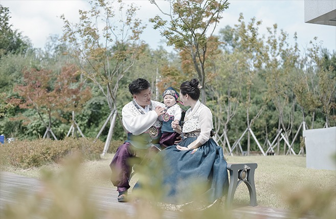 야외 공원 벤치 3인 가족 돌스냅 — 한복 차림 전체 컷