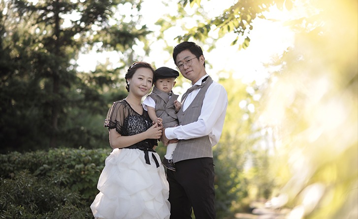 야외 황금빛 역광 — 3인 가족, 나무 사이 오후 햇살